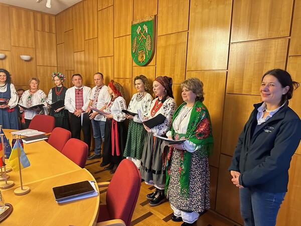 Bild vergrößern: Ein ukrainischer Chor in farbenfrohen Landestrachten stehen im holzgetfelten Ratssaal unter dem Wappen der Samtgemeinde Wathlingen.